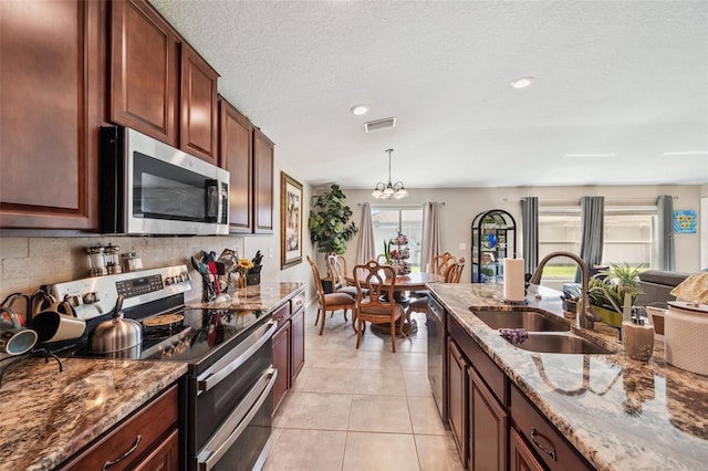 kitchen with light stone counters, decorative backsplash, stainless steel appliances, and a sink