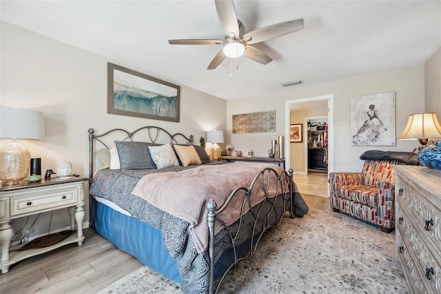 bedroom featuring a ceiling fan, visible vents, a spacious closet, and wood finished floors