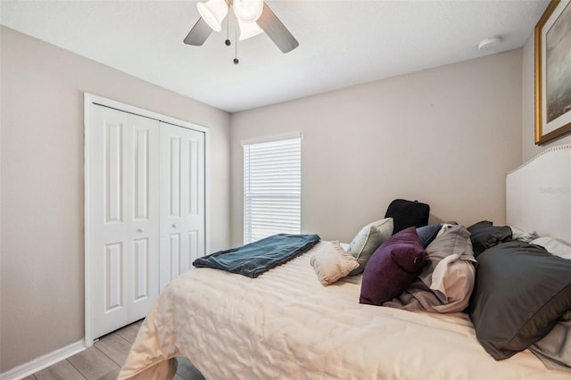 bedroom featuring light wood-type flooring, a closet, ceiling fan, and baseboards