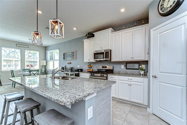 kitchen featuring stainless steel appliances, a sink, white cabinets, and a kitchen breakfast bar