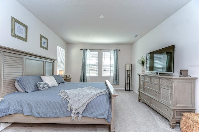 bedroom with baseboards, visible vents, and light colored carpet