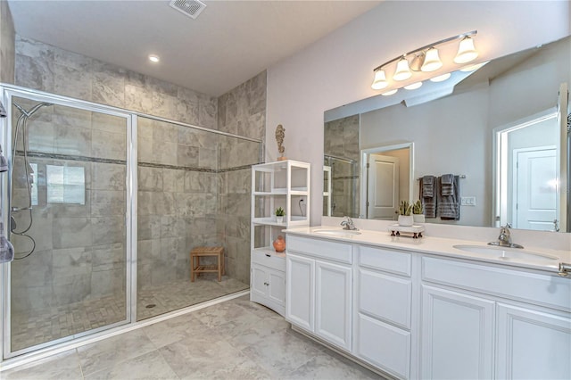 full bath featuring double vanity, a shower stall, visible vents, and a sink