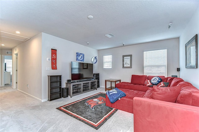 living area featuring a textured ceiling, visible vents, baseboards, carpet, and attic access