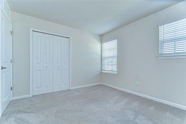 unfurnished bedroom with a closet, carpet flooring, and baseboards