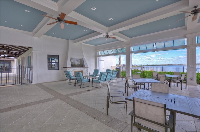 view of patio with a water view, fence, a ceiling fan, and outdoor dining space