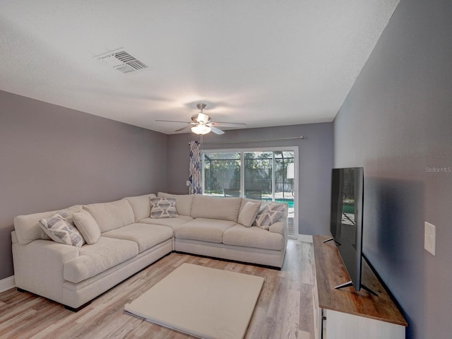 living area featuring light wood finished floors, baseboards, visible vents, and a ceiling fan