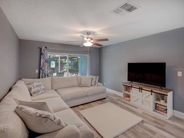 living area featuring visible vents, ceiling fan, a textured ceiling, wood finished floors, and baseboards