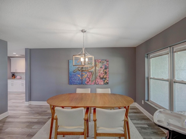 dining area featuring a chandelier, wood finished floors, and baseboards