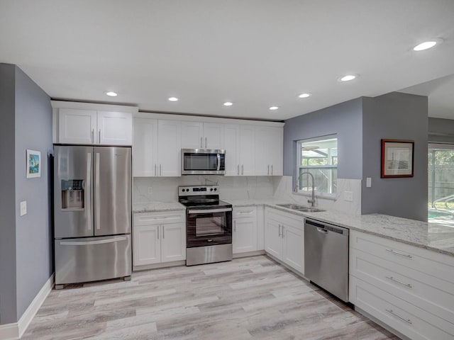 kitchen with stainless steel appliances, tasteful backsplash, a sink, and light stone countertops