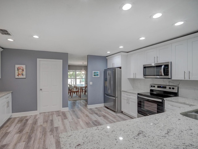 kitchen featuring light stone counters, stainless steel appliances, visible vents, white cabinets, and tasteful backsplash