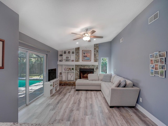 living area featuring a fireplace, visible vents, baseboards, vaulted ceiling, and light wood-type flooring