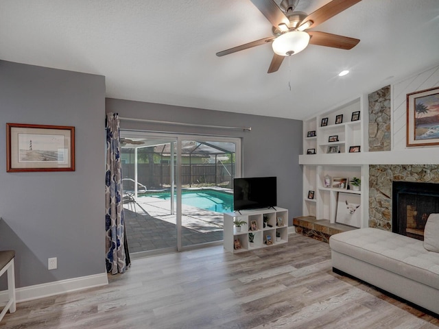 living room with a fireplace, wood finished floors, baseboards, vaulted ceiling, and built in features