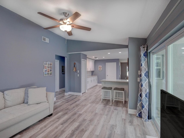 living room featuring lofted ceiling, light wood-style flooring, visible vents, and baseboards