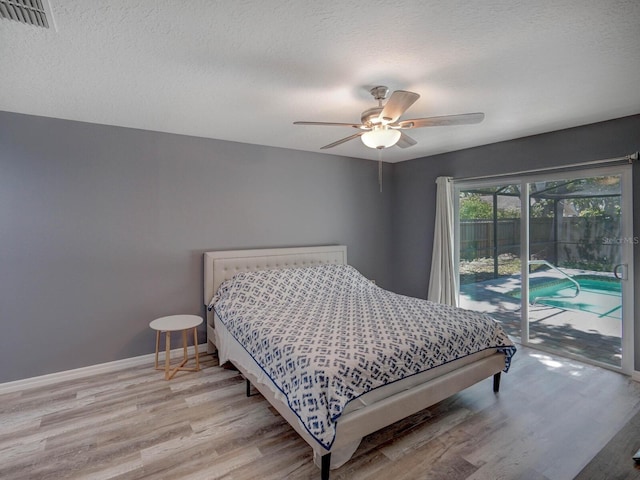 bedroom featuring access to outside, a textured ceiling, baseboards, and wood finished floors