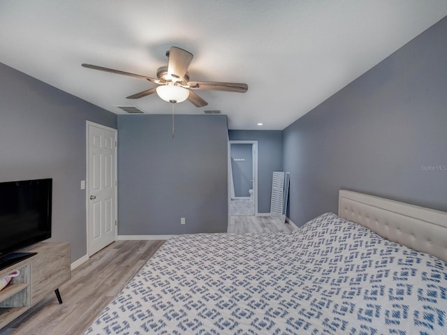 bedroom featuring baseboards, visible vents, ceiling fan, and wood finished floors