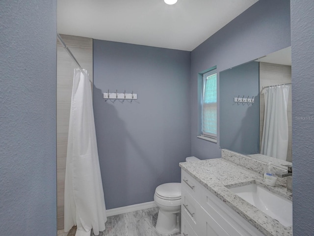 bathroom featuring curtained shower, vanity, toilet, and baseboards