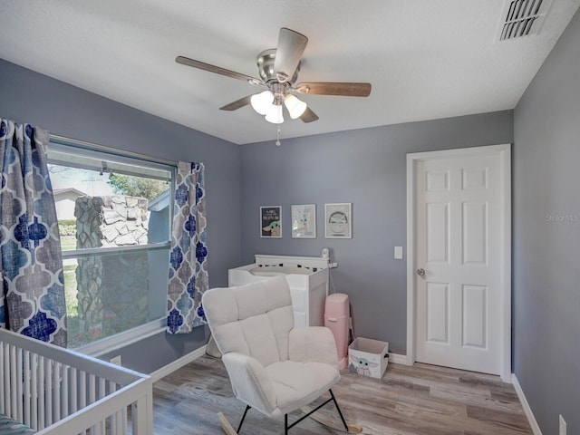 bedroom with baseboards, visible vents, ceiling fan, and wood finished floors