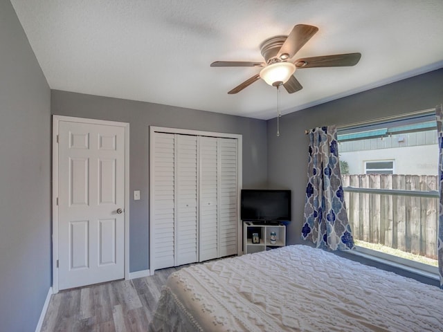 unfurnished bedroom featuring a ceiling fan, a closet, baseboards, and wood finished floors