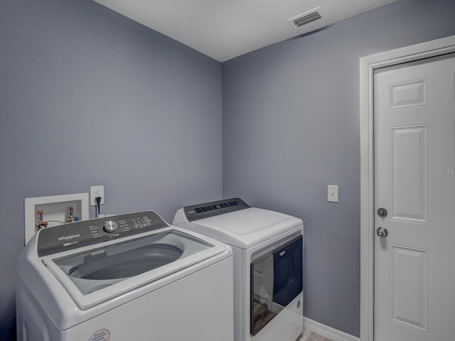 laundry room with laundry area, washer and clothes dryer, visible vents, and baseboards