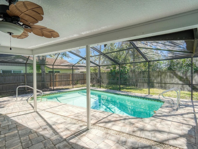 view of swimming pool with a patio, glass enclosure, a fenced backyard, a ceiling fan, and a fenced in pool