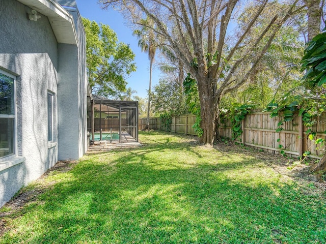 view of yard featuring glass enclosure and a fenced backyard