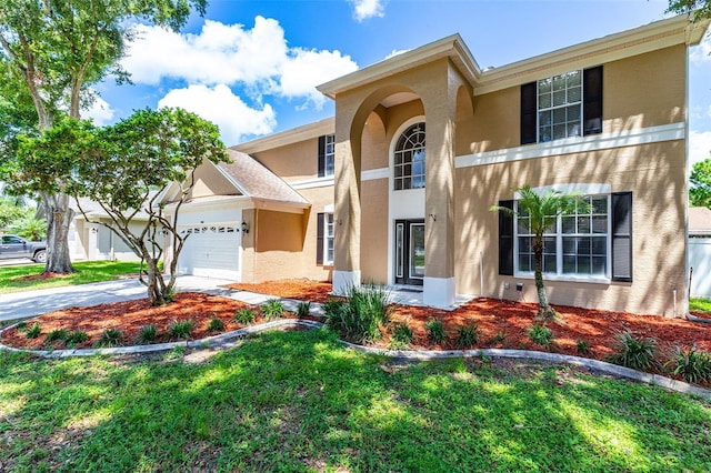 traditional-style home featuring a front lawn, driveway, an attached garage, and stucco siding