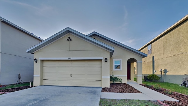 ranch-style home featuring stucco siding, a garage, and concrete driveway