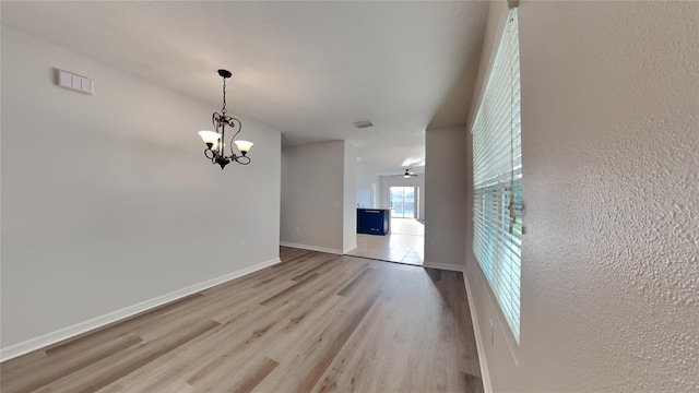 unfurnished dining area with light wood-type flooring, baseboards, and a chandelier