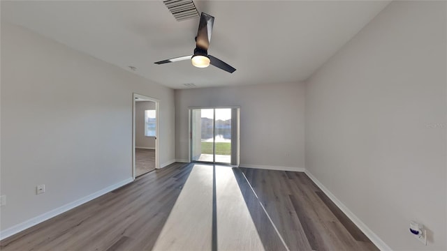 spare room featuring visible vents, a ceiling fan, baseboards, and wood finished floors