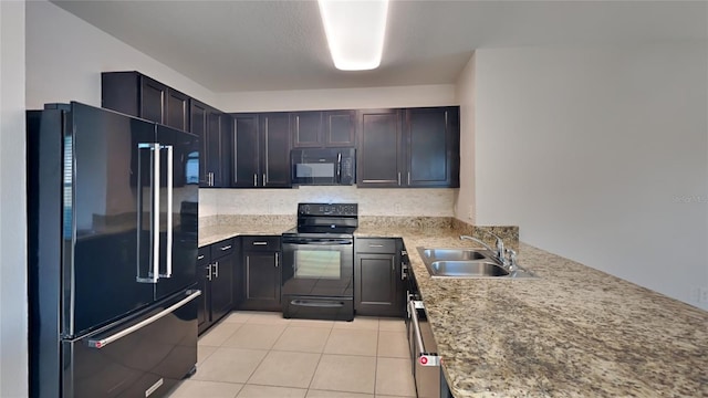 kitchen with light tile patterned floors, light stone countertops, a peninsula, a sink, and black appliances