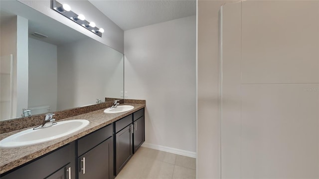 bathroom featuring double vanity, visible vents, toilet, and a sink