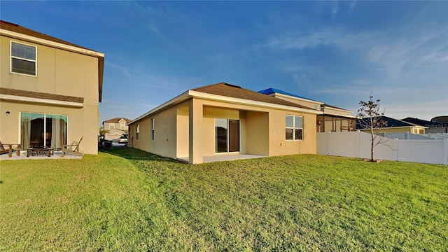 back of property featuring a patio area, stucco siding, a yard, and fence