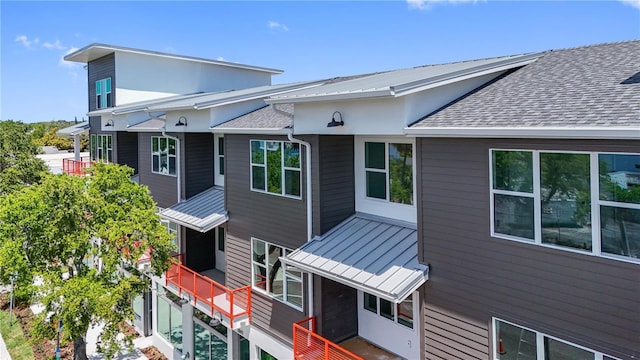 exterior space with a standing seam roof, roof with shingles, and metal roof