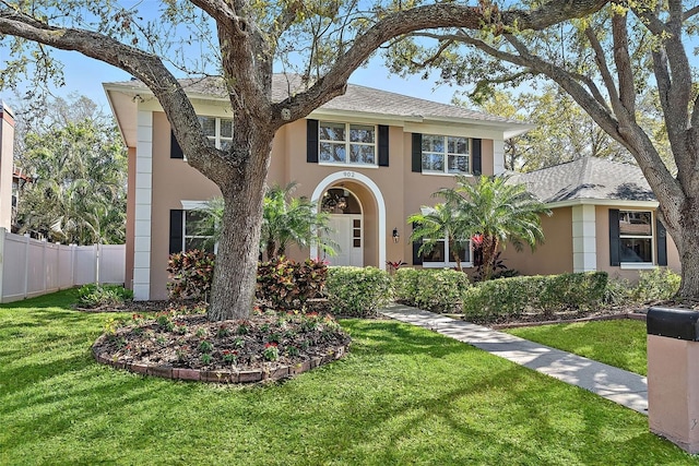 view of front of home with a shingled roof, a front yard, fence, and stucco siding