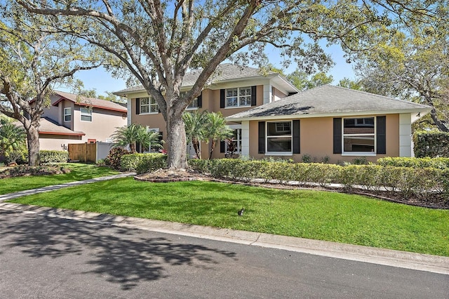 view of front of home with a front lawn, fence, and stucco siding