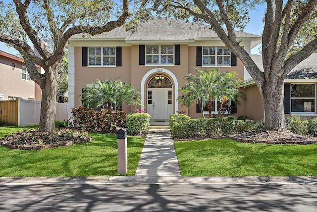 view of front of property featuring stucco siding, a front yard, and fence