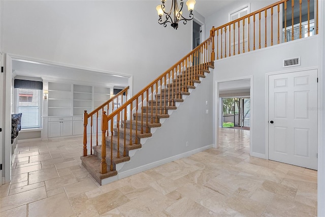 stairs featuring visible vents, baseboards, a chandelier, stone tile floors, and a high ceiling