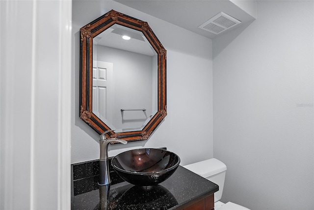 half bathroom featuring visible vents, toilet, and vanity