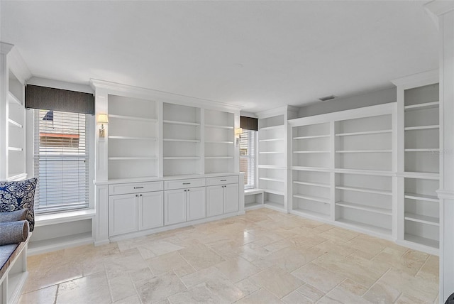 spare room featuring visible vents, stone finish flooring, and built in features