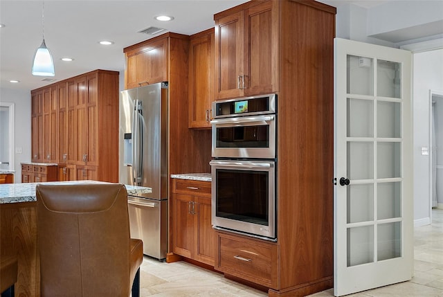 kitchen with brown cabinetry, stainless steel appliances, and light stone countertops