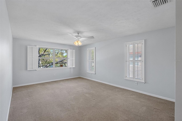 carpeted spare room featuring visible vents, ceiling fan, a textured ceiling, and baseboards