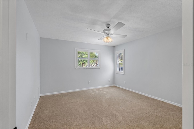 carpeted empty room featuring baseboards, a textured ceiling, and ceiling fan