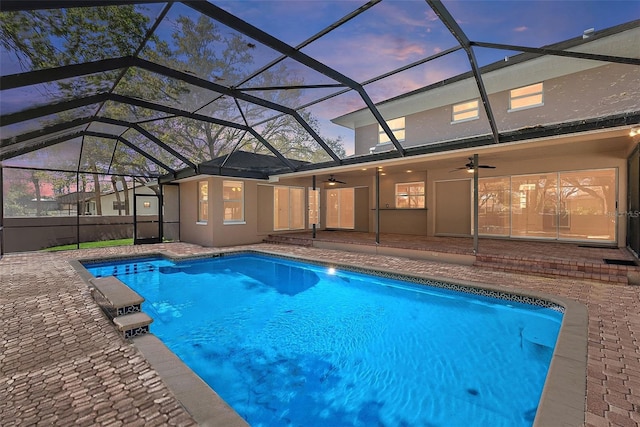 pool at dusk featuring an outdoor pool, a lanai, a ceiling fan, and a patio area