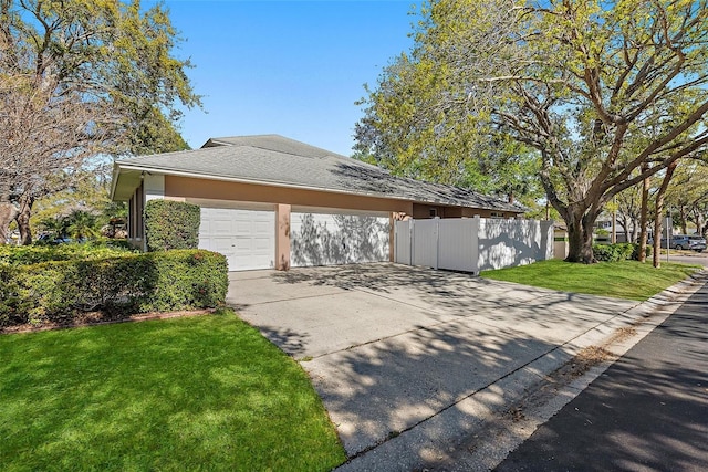 view of side of property with fence, roof with shingles, driveway, stucco siding, and a lawn