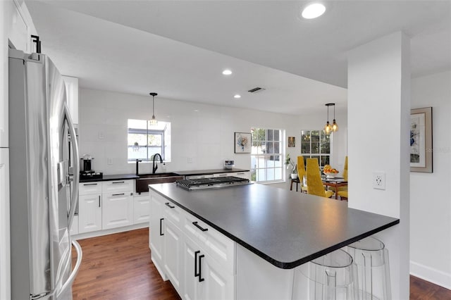 kitchen with stainless steel appliances, dark countertops, visible vents, and a sink