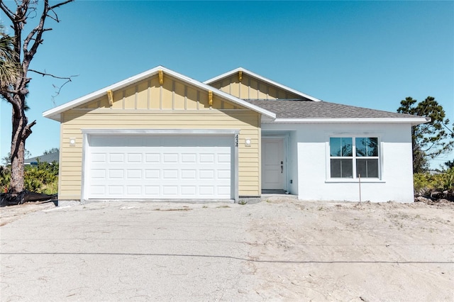 single story home featuring board and batten siding, roof with shingles, driveway, and a garage