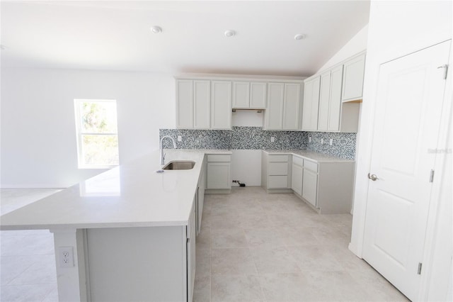 kitchen featuring tasteful backsplash, lofted ceiling, light countertops, and a sink