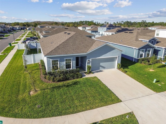 single story home with a garage, fence, concrete driveway, a residential view, and a front yard