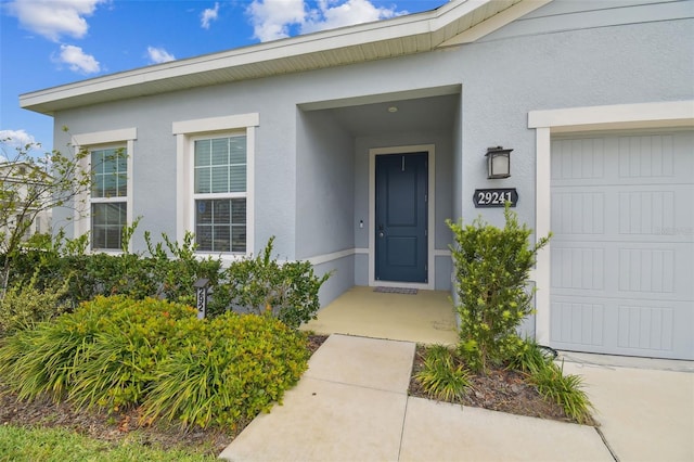 property entrance featuring an attached garage and stucco siding