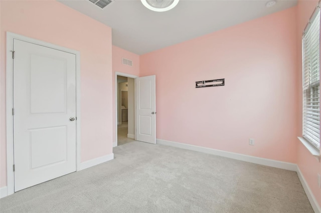 unfurnished bedroom featuring visible vents, baseboards, and light colored carpet